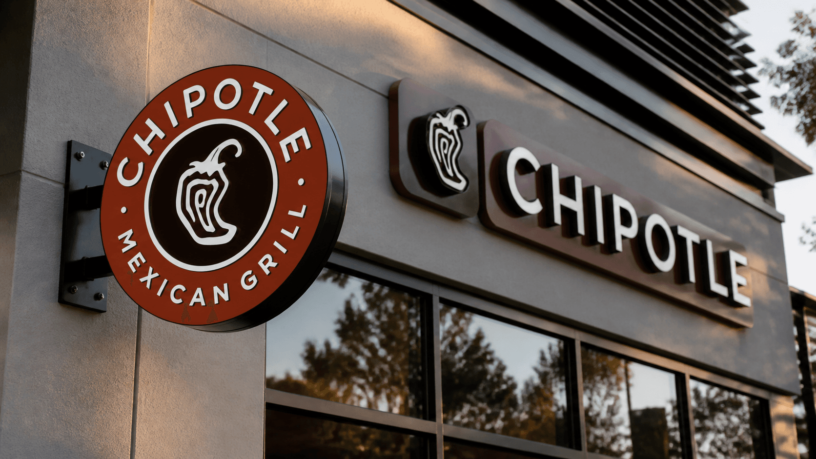 A close-up of a Chipotle sign outside a modern restaurant storefront