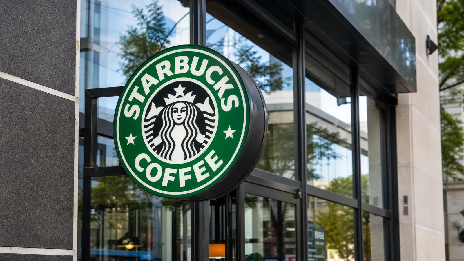 A close-up of a Starbucks Coffee sign outside a modern cafe storefront