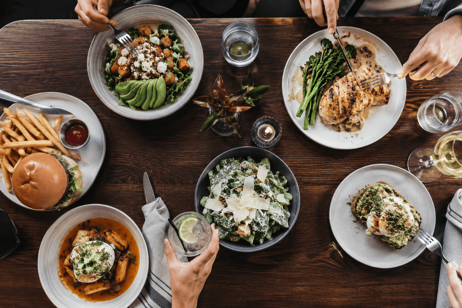 A restaurant table with a balanced meal, water glass, menu, and phone for mindful meal tracking