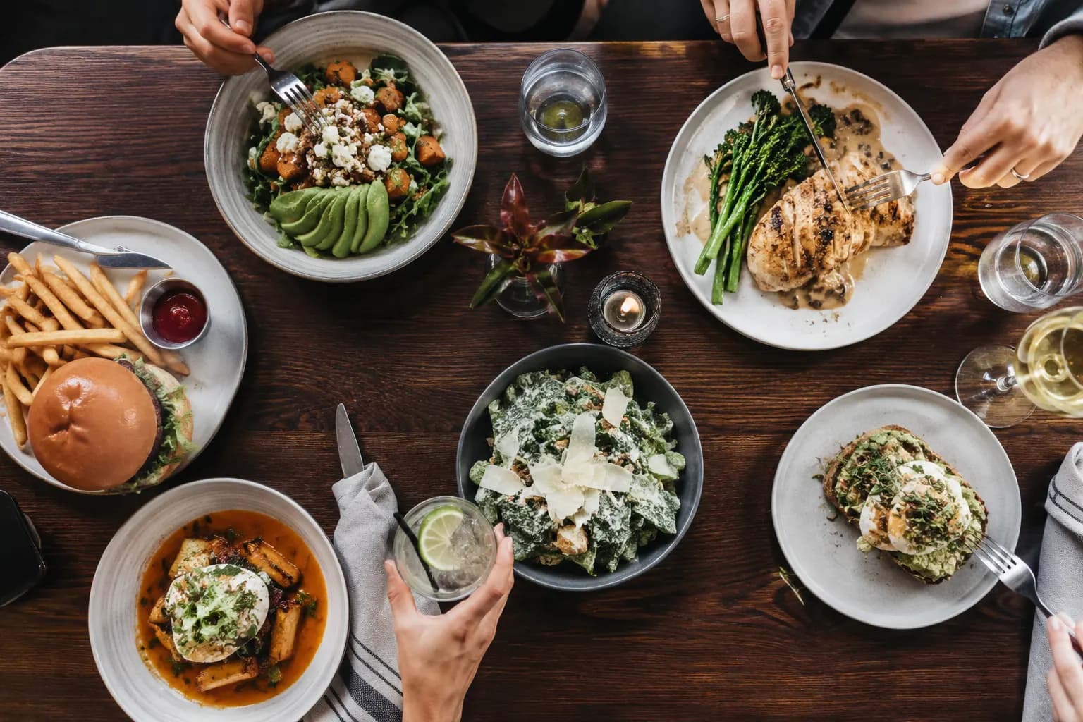 A restaurant table with a balanced meal, water glass, menu, and phone for mindful meal tracking
